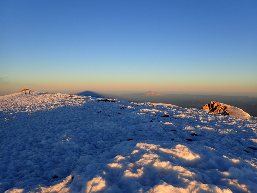 Mount St. Helens and Mount Adams' own shadow on the ground.